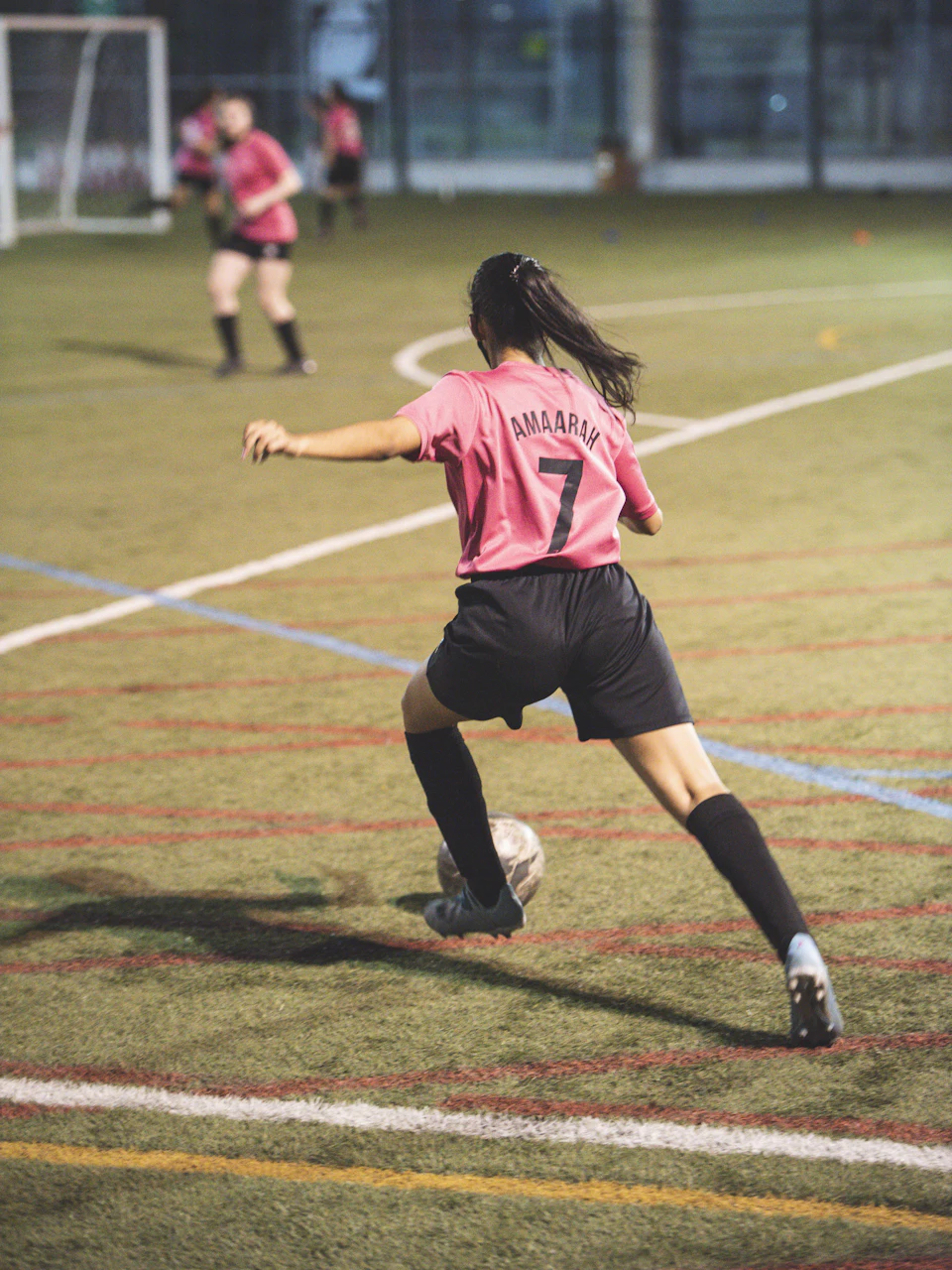 A soccer player striking the ball under the lights